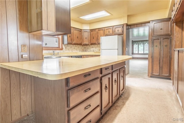14309 Maple St, Diana, NY 13648 - kitchen with freestanding refrigerator, light countertops, light colored carpet, and brown cabinetry