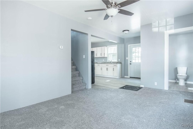 807 Bingham Ave, Watertown City, NY 13601 - unfurnished living room featuring a ceiling fan, light colored carpet, and stairway