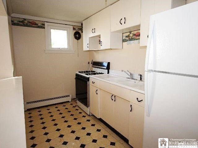 515 Newland Ave, Jamestown, NY 14701 - kitchen with white appliances, baseboard heating, light countertops, light flooring, and white cabinetry