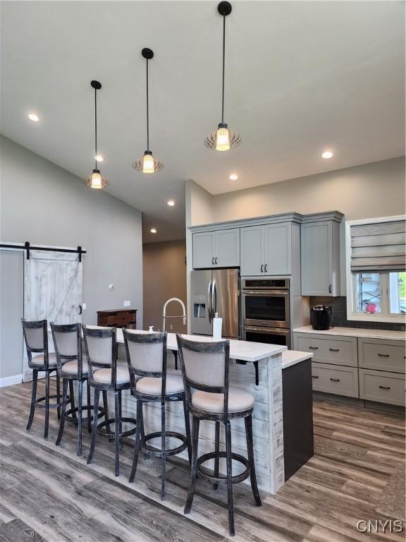 1683 Song Mountain Rd, Preble, NY 13141 - kitchen featuring appliances with stainless steel finishes, gray cabinets, dark wood-style floors, light countertops, and a kitchen bar