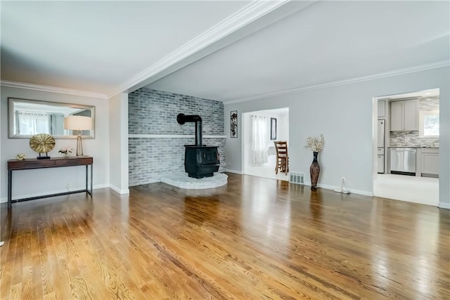 138 Cherry Rd, Rochester, NY 14612 - unfurnished living room featuring crown molding, a wood stove, and light wood-style floors