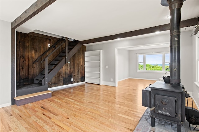 5808 W Wautoma Beach Rd, Hamlin, NY 14468 - unfurnished living room with a wood stove, wood finished floors, stairway, and beamed ceiling
