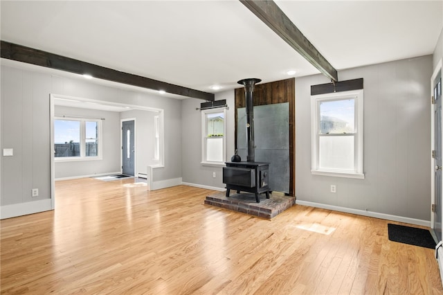 5808 W Wautoma Beach Rd, Hamlin, NY 14468 - unfurnished living room featuring beam ceiling, light wood-style floors, a wood stove, and plenty of natural light