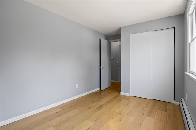 5808 W Wautoma Beach Rd, Hamlin, NY 14468 - unfurnished bedroom with a baseboard radiator, light wood-style flooring, a closet, and multiple windows