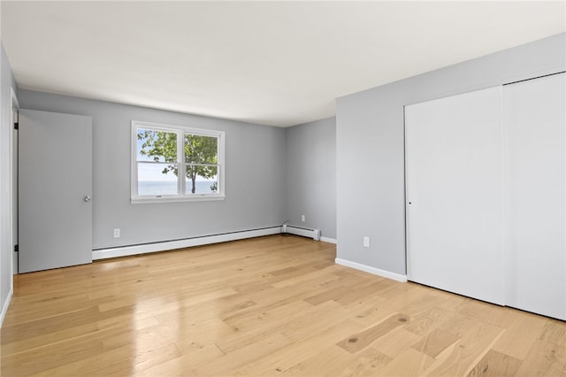 5808 W Wautoma Beach Rd, Hamlin, NY 14468 - unfurnished bedroom featuring baseboard heating, light wood finished floors, and a closet