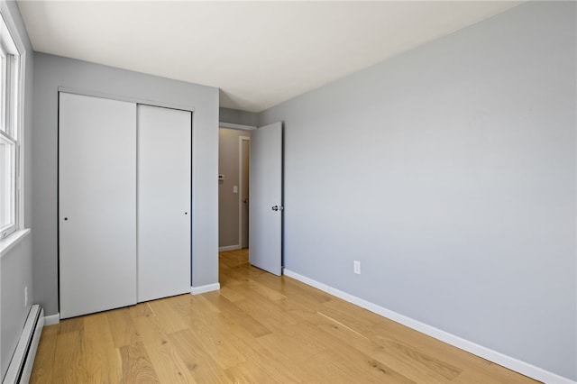 5808 W Wautoma Beach Rd, Hamlin, NY 14468 - unfurnished bedroom featuring baseboard heating, light wood-style floors, and a closet