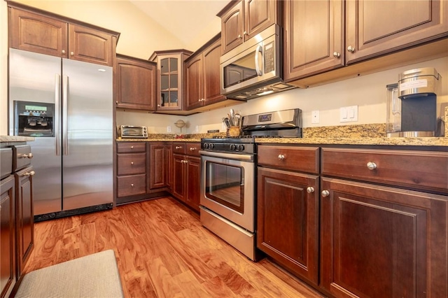 246 Maryview Dr, Penfield, NY 14580 - kitchen with stainless steel appliances, light wood finished floors, light stone countertops, vaulted ceiling, and glass insert cabinets