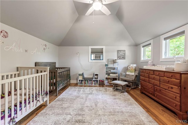 1848 Otisco Valley Rd, Otisco, NY 13110 - bedroom with wood finished floors, lofted ceiling, a wall mounted air conditioner, a crib, and a ceiling fan