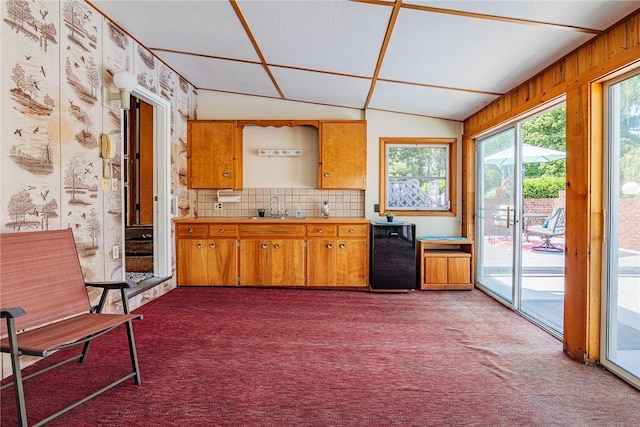 164 Queens Ln, Irondequoit, NY 14617 - kitchen featuring carpet, vaulted ceiling, backsplash, brown cabinetry, and light countertops