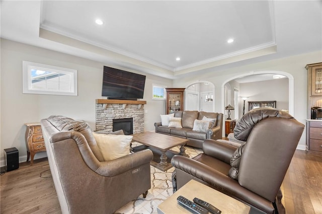 905 Pathway Ln, Webster, NY 14580 - living room with a raised ceiling, arched walkways, light wood-type flooring, a stone fireplace, and crown molding