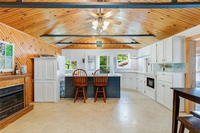 1753 Log Cabin Rd, Torrey, NY 14527 - kitchen featuring black microwave, vaulted ceiling, a breakfast bar area, white cabinets, and wooden ceiling