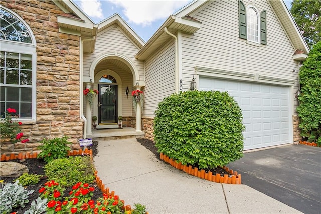 801 Surrey Hill Way, Henrietta, NY 14623 - doorway to property featuring stone siding, driveway, and a garage
