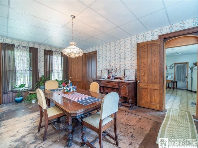 12 Central Ave, Portland, NY 14716 - dining area featuring wallpapered walls, a chandelier, wood finished floors, and a drop ceiling