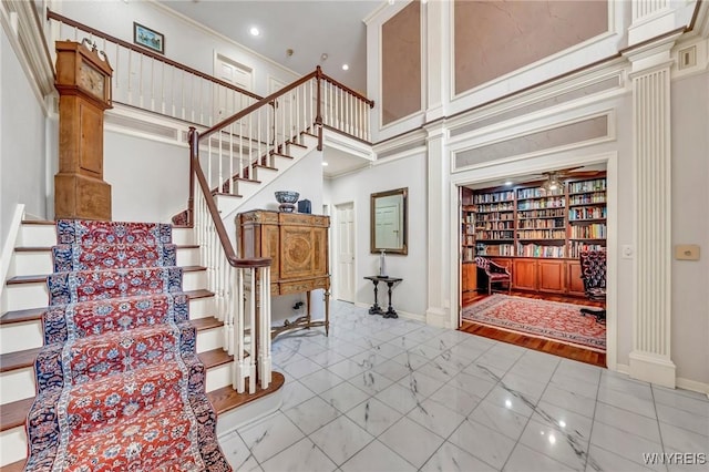 9555 The Maples, Clarence, NY 14031 - staircase featuring decorative columns, a high ceiling, crown molding, marble finish floors, and recessed lighting