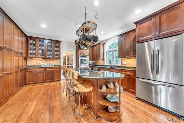 9555 The Maples, Clarence, NY 14031 - kitchen with stainless steel appliances, backsplash, light wood-style floors, dark stone countertops, and a kitchen breakfast bar