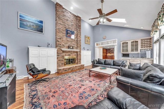 9555 The Maples, Clarence, NY 14031 - living room with high vaulted ceiling, ceiling fan, light wood finished floors, a skylight, and a brick fireplace