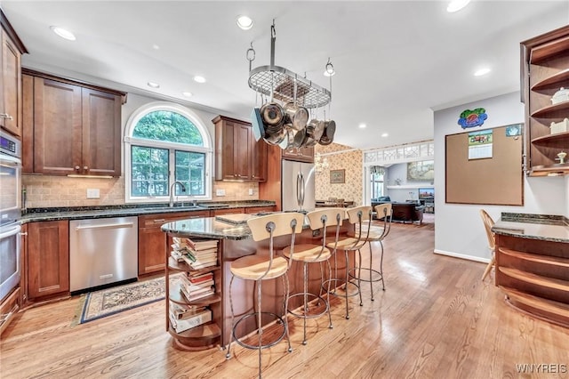 9555 The Maples, Clarence, NY 14031 - kitchen featuring stainless steel appliances, open shelves, dark stone counters, a kitchen bar, and light wood finished floors