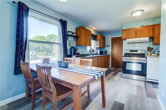 85 Campfire Rd N, Henrietta, NY 14467 - kitchen with stainless steel gas range, under cabinet range hood, dishwasher, brown cabinetry, and wood finished floors