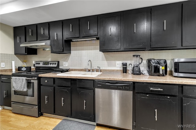 335 S Cayuga Rd Unit B, Amherst, NY 14221 - kitchen with stainless steel appliances, ventilation hood, dark cabinetry, light countertops, and tasteful backsplash