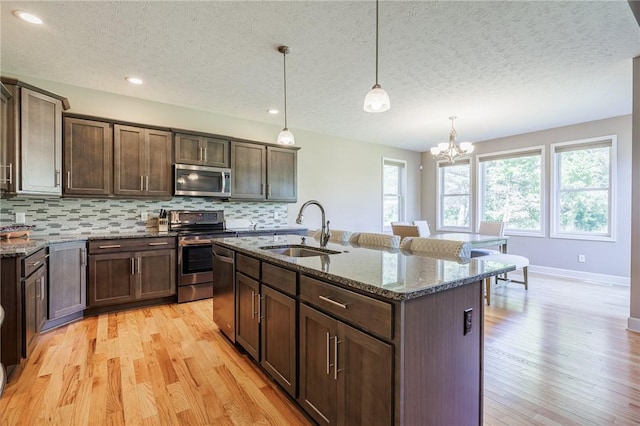996 Summer Creek Ln, Webster, NY 14580 - kitchen featuring appliances with stainless steel finishes, a textured ceiling, light wood-type flooring, decorative backsplash, and dark stone countertops
