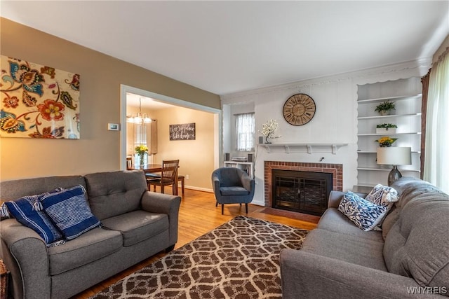 29 Charlestown Rd, Amherst, NY 14226 - living room with light wood finished floors, a brick fireplace, and a chandelier