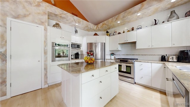 6097 Wellesley Cmn, Clarence, NY 14051 - kitchen featuring stainless steel appliances, lofted ceiling, light wood-style flooring, a center island, and light stone counters
