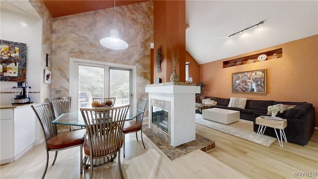 6097 Wellesley Cmn, Clarence, NY 14051 - dining area featuring rail lighting, light wood-type flooring, a premium fireplace, and high vaulted ceiling