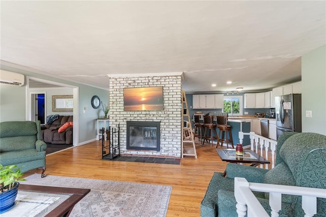 1015 Wayneport Rd, Macedon, NY 14502 - living area featuring a wall mounted AC, light wood-style floors, a brick fireplace, and ornamental molding