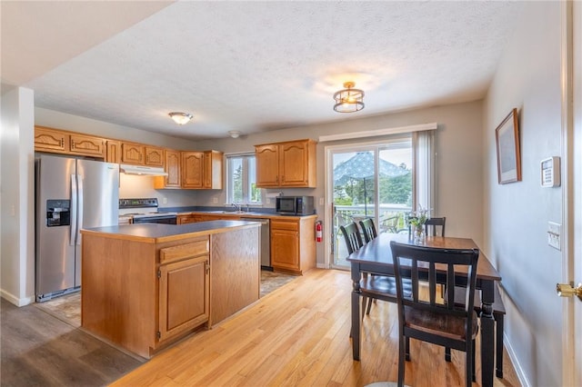 11 Wenrich Cir, Henrietta, NY 14586 - kitchen with stainless steel appliances, under cabinet range hood, light wood-type flooring, a kitchen island, and a textured ceiling