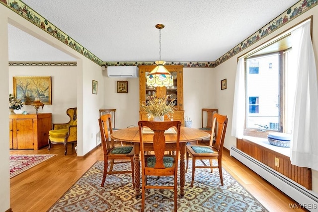 1581 N Forest Rd, Amherst, NY 14221 - dining area with a baseboard heating unit, a wall mounted AC, a textured ceiling, healthy amount of natural light, and light wood-style floors