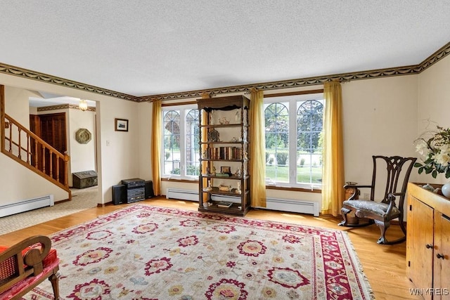 1581 N Forest Rd, Amherst, NY 14221 - sitting room featuring a baseboard radiator, a textured ceiling, stairs, and wood finished floors