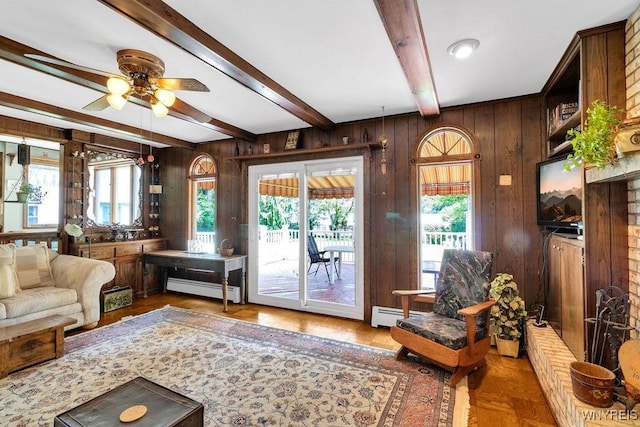 1581 N Forest Rd, Amherst, NY 14221 - living room featuring beamed ceiling, healthy amount of natural light, baseboard heating, wooden walls, and a ceiling fan