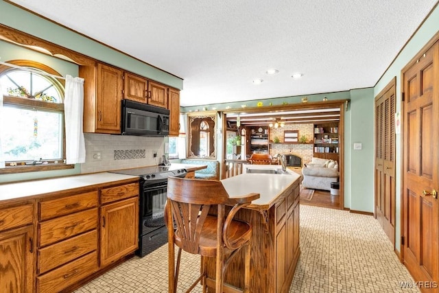 1581 N Forest Rd, Amherst, NY 14221 - kitchen with black appliances, brown cabinetry, light countertops, backsplash, and a textured ceiling