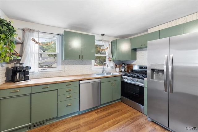 102 Bramley Dr, Camillus, NY 13031 - kitchen with stainless steel appliances, green cabinetry, decorative backsplash, and light wood finished floors