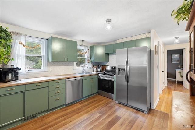 102 Bramley Dr, Camillus, NY 13031 - kitchen featuring appliances with stainless steel finishes, green cabinetry, decorative backsplash, and light wood-style floors