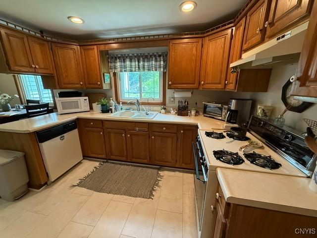 4050 Elmcrest Rd, Salina, NY 13090 - kitchen featuring white microwave, dishwashing machine, under cabinet range hood, range with gas cooktop, and brown cabinetry