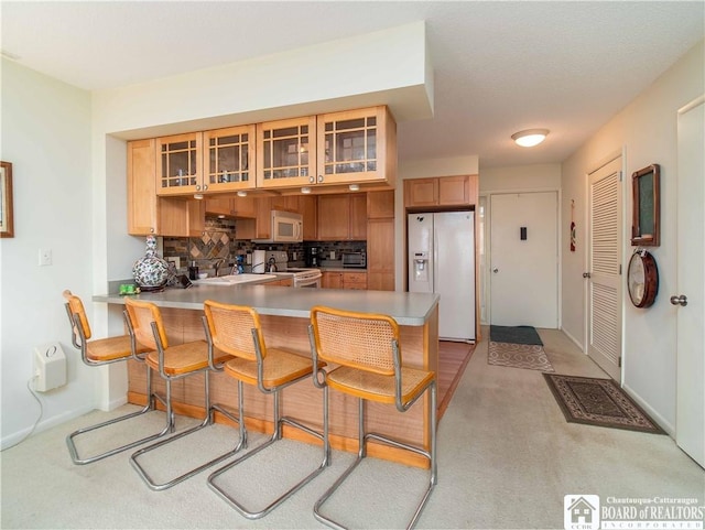 38 Oneida Dr, Chautauqua, NY 14728 - kitchen with white appliances, a peninsula, light countertops, light colored carpet, and glass insert cabinets