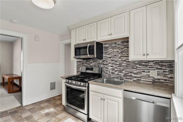 532 Linden Ave, Buffalo, NY 14216 - kitchen with stainless steel appliances, tasteful backsplash, light countertops, stone finish floors, and a wainscoted wall