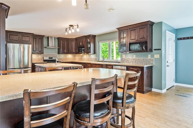 184 Main St, Phelps, NY 14532 - kitchen with appliances with stainless steel finishes, wall chimney exhaust hood, light countertops, decorative backsplash, and dark brown cabinets
