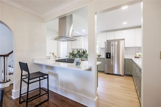 240 Sagamore Dr, Irondequoit, NY 14617 - kitchen with stainless steel fridge with ice dispenser, island exhaust hood, tasteful backsplash, gray cabinetry, and light countertops