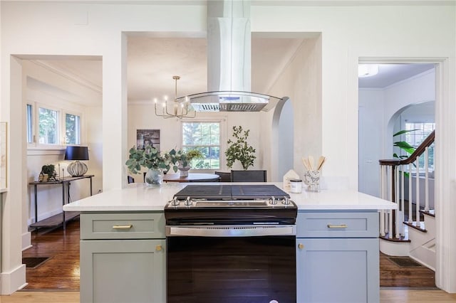 240 Sagamore Dr, Irondequoit, NY 14617 - kitchen with stainless steel gas stove, arched walkways, island range hood, crown molding, and a chandelier