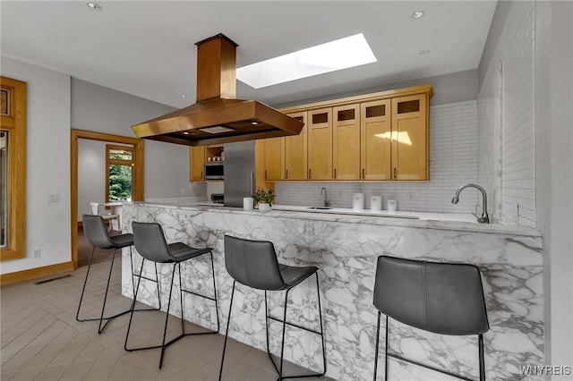 7 Lebrun Cir, Amherst, NY 14226 - kitchen featuring island exhaust hood, a skylight, stainless steel microwave, a kitchen breakfast bar, and recessed lighting