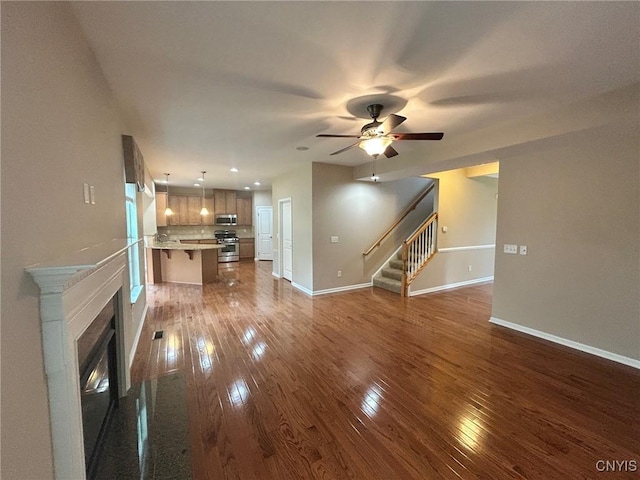 107 Shaker Hts, Camillus, NY 13031 - unfurnished living room with dark wood-type flooring, a ceiling fan, stairs, and a glass covered fireplace