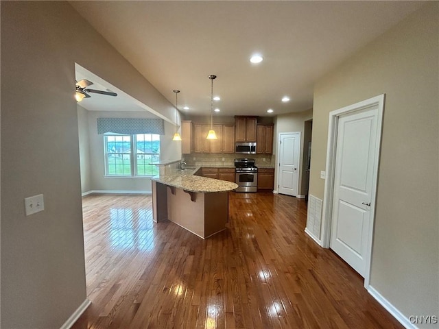 107 Shaker Hts, Camillus, NY 13031 - kitchen with appliances with stainless steel finishes, a peninsula, dark wood finished floors, tasteful backsplash, and decorative light fixtures