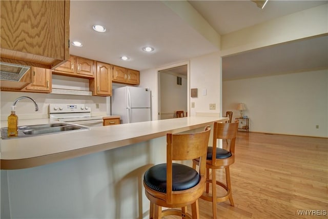 1175 Youngs Rd Unit C, Amherst, NY 14221 - kitchen with white appliances, a peninsula, light wood finished floors, a breakfast bar area, and light countertops