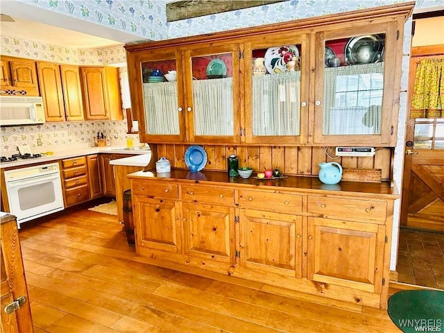 2721 Bowen Rd, Elma, NY 14059 - kitchen featuring wallpapered walls, white appliances, light wood finished floors, brown cabinets, and backsplash