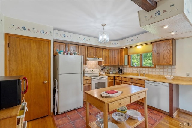 206 Oswego River Rd, Schroeppel, NY 13135 - kitchen featuring white appliances, under cabinet range hood, decorative backsplash, light countertops, and a chandelier