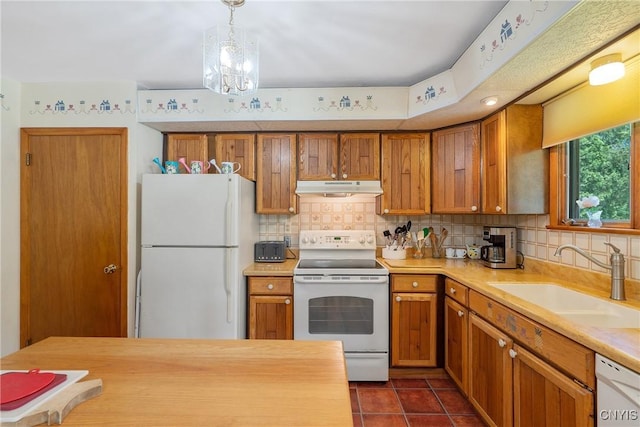 206 Oswego River Rd, Schroeppel, NY 13135 - kitchen with white appliances, under cabinet range hood, brown cabinets, decorative backsplash, and dark tile patterned flooring