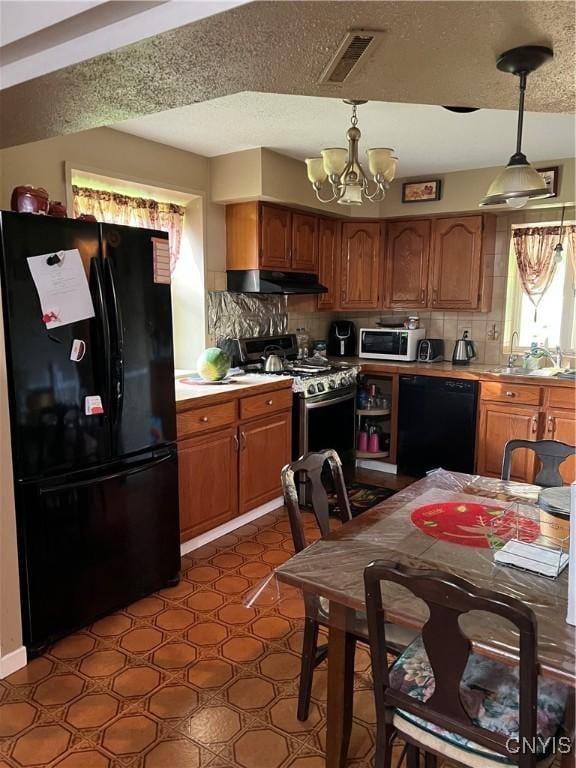 4067 Taylor Rd, Pompey, NY 13078 - kitchen with black appliances, under cabinet range hood, a chandelier, light countertops, and brown cabinetry