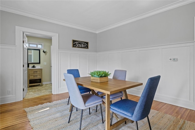 234 Pine Grove Ave, Irondequoit, NY 14617 - dining space featuring a decorative wall, light wood finished floors, ornamental molding, and wainscoting